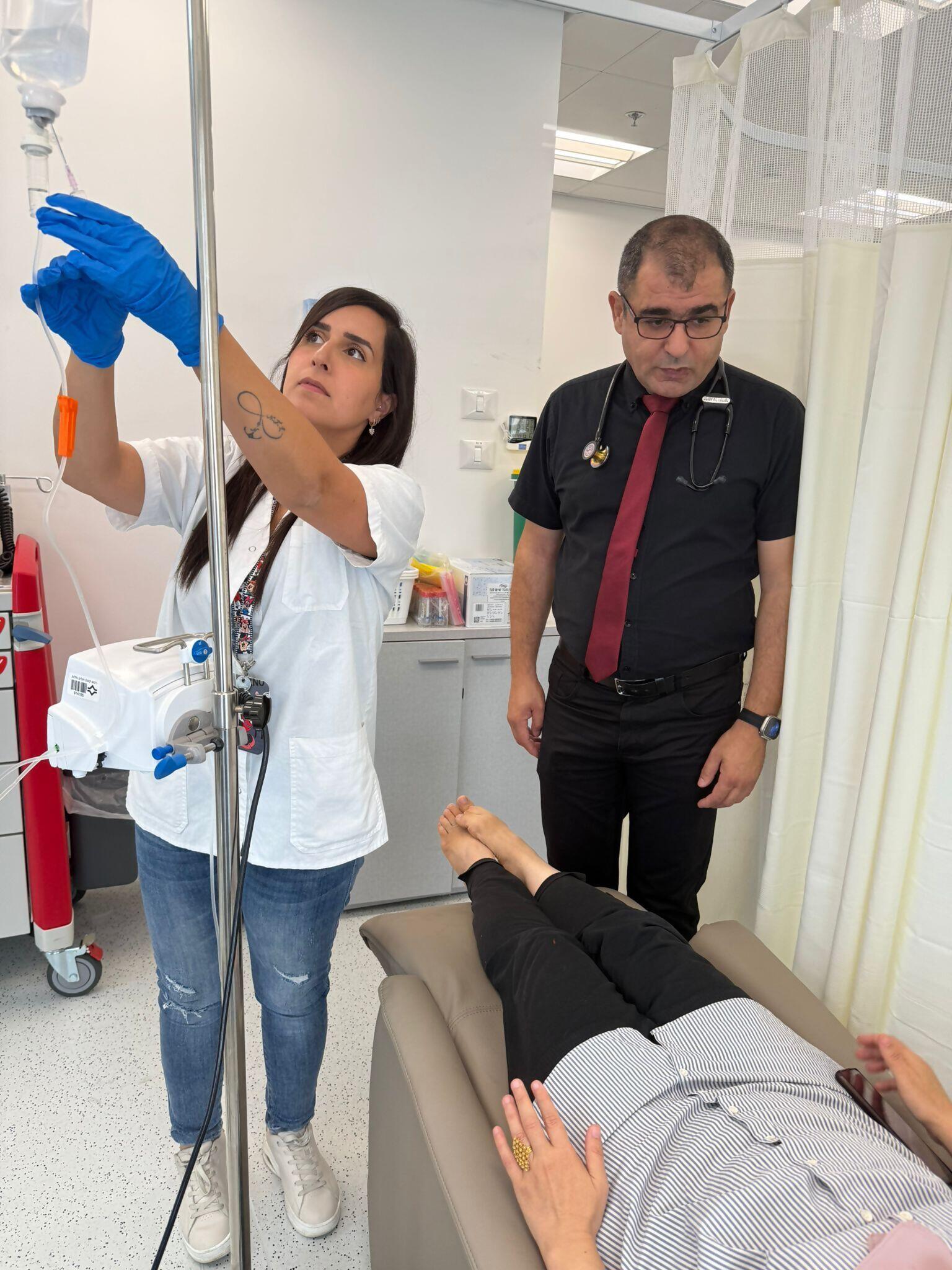 ד"ר נביה יוסף ואחות ליד מיטת מטופל בחדר טיפולים
